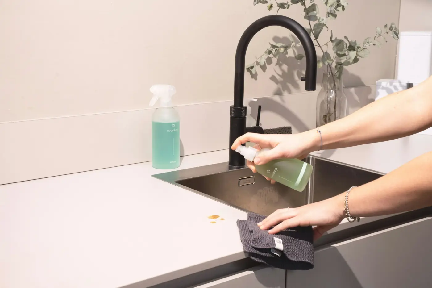 Hands wiping a kitchen sink clean